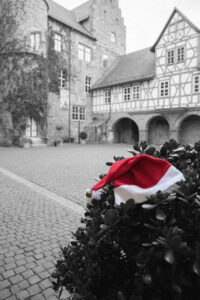 Innenhof mit Schoss, davor ein Busch, auf dem eine Weihnachtsmütze gelegt wurde
