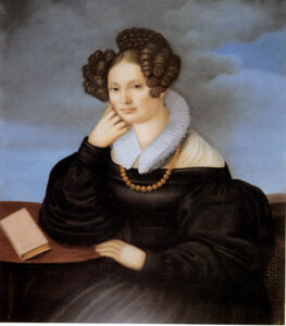 Porträtbild von Minna Meyer. Frau stützt sich auf ihren Arm, vor ihr auf dem Tisch ein Buch.